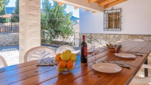 a wooden table with a bottle of wine and a bowl of fruit at Casa de Paquita Montefrio by Ruralidays in Montefrío