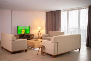 un soggiorno con 2 sedie e una TV a schermo piatto di Luxurious Penthouse With Luxurious Pool a Sekondi-Takoradi