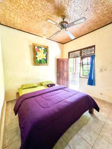 una camera con letto viola e ventilatore a soffitto di Leket house ad Ubud