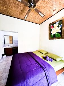 una camera con letto viola e ventilatore a soffitto di Leket house ad Ubud