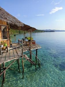 een pier met tafels en stoelen in het water bij Yenbainus homestay in Yennanas Besir