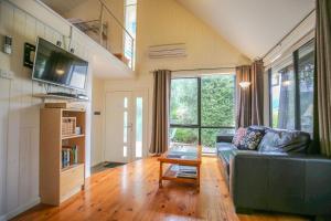 a living room with a couch and a table at Allambie Cottages - Villa 1 in Bright