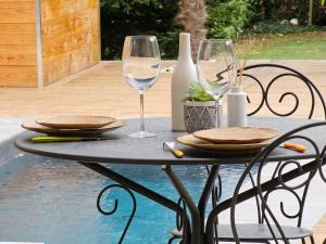 una mesa con platos y copas de vino en una mesa junto a la piscina en Un moment de détente, en Gilly-sur-Isère