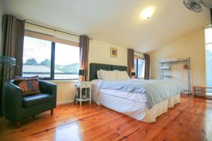 a bedroom with a bed and a chair and a window at Allambie Cottages - Villa 1 in Bright