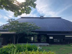 un bâtiment avec un toit noir et un arbre dans l'établissement Kuroishi - House - Vacation STAY 87006, à Kuroishi