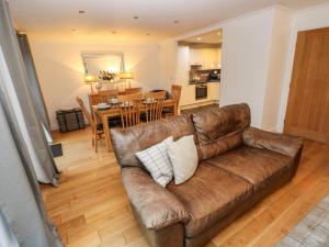 a living room with a brown couch and a dining room at Goldfinch in Milford Haven