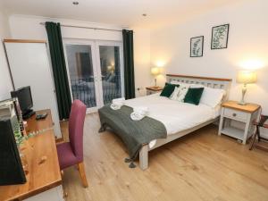 a bedroom with a bed and a desk and a tv at Goldfinch in Milford Haven