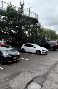 dos autos blancos estacionados en un estacionamiento en The King Stay, en Mánchester