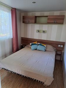 a bedroom with a large bed with blue pillows at Camping Le Soulhol in Saint-Céré