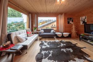 ein Wohnzimmer mit einem Sofa und einem großen Fenster in der Unterkunft Chalet aux Cerfs - Maison pour 10 vue montagne in Arâches-la-Frasse