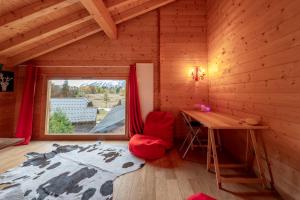 Cette chambre dispose d'un bureau, d'une chaise rouge et d'une fenêtre. dans l'établissement Chalet aux Cerfs - Maison pour 10 vue montagne, à Arâches-la-Frasse