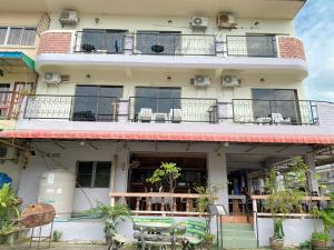 a building with a balcony with tables and chairs at 2 Vikings Guesthouse in Karon Beach