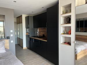 eine Küche mit schwarzen Schränken und ein Bett in einem Zimmer in der Unterkunft Appartement Village Naturiste Sensuel in Cap d'Agde