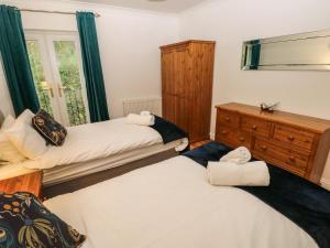 1 dormitorio con 2 camas, tocador y espejo en Heron, en Milford Haven
