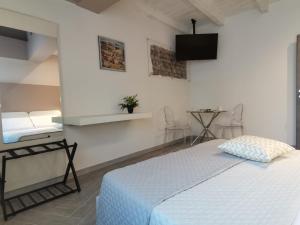a white bedroom with a bed and a table at Green Guest House in Oristano