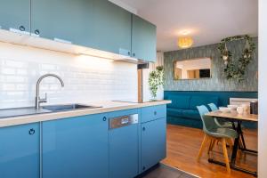 a kitchen with blue cabinets and a table with chairs at La station n° 5 in Annecy