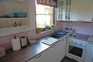 a kitchen with white cabinets and a sink and a window at Ostoja Bukowo, Domek 9,1 'Stilia' in Borowy Młyn