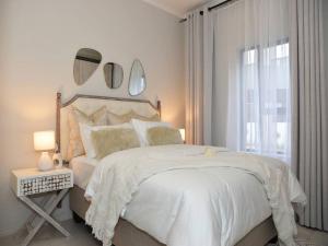 a white bedroom with a large bed and a window at Elcaro Luxury Villas-Royal Abode in Midrand