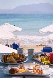 a table with three plates of food on the beach at Faedra Beach in Agios Nikolaos