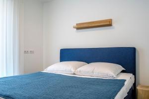 a bed with a blue headboard and white pillows at Park-Apartment Scharmützelsee Wohnung 5 in Wendisch Rietz