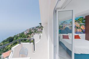 a balcony with a bed and a view of the city at Albergo Dipinto BaccoFurore in Furore