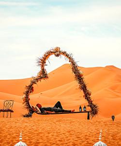 a man laying on a bed in the desert at Fabulous luxury camp in Merzouga