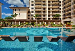 a swimming pool with chairs and a large building at Ko Olina Beach Villas O414 in Kapolei