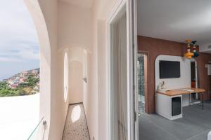 a room with a balcony with a desk and a television at Albergo Dipinto BaccoFurore in Furore