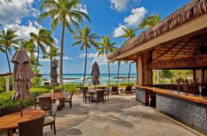 a patio with tables and chairs and the beach at Ko Olina Beach Villas O414 in Kapolei