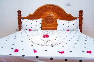 a bed with a wooden headboard and pink flowers on it at Bara Accommodations Paje in Paje