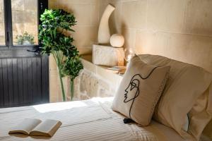Una cama con dos almohadas y un libro. en Charming & Stylish Historic Farmhouse with Pool, en Xewkija