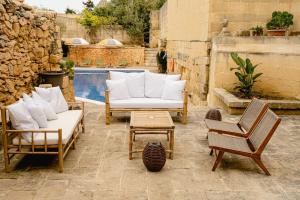patio con sofá, sillas y piscina en Charming & Stylish Historic Farmhouse with Pool, en Xewkija