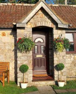 a house with a brown door and two potted plants at Cosy & Characterful, Seaside Cottage, Dog Friendly in Worle