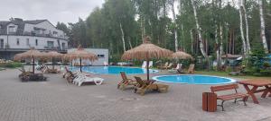 a group of chairs and umbrellas and a swimming pool at Apartament Riva in Pobierowo