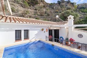 a house with a swimming pool in front of a mountain at Apartment private swimming pool in Frigiliana
