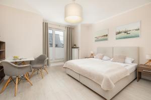 biała sypialnia z łóżkiem, biurkiem i krzesłami w obiekcie Apartamenty Aquamarina by Noclegi Renters w Świnoujściu