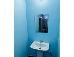 La salle de bains bleue est pourvue d'un lavabo et d'un miroir. dans l'établissement Hotel Hans Deep, Phata, à Phata