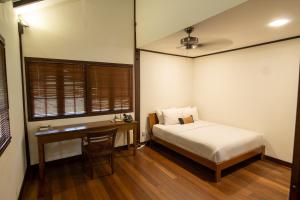 1 dormitorio con cama, escritorio, cama y ventana en Nongsa Village en Nongsa