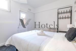 um quarto branco com uma cama com uma placa de hotel em AYZ Ulises - Auto check-in property em Madrid