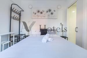 Un dormitorio con una cama blanca con toallas. en AYZ Ulises - Auto check-in property, en Madrid