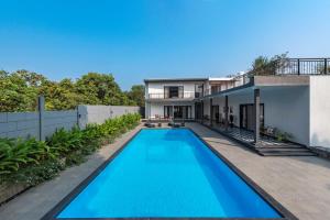an image of a swimming pool in the backyard of a house at SaffronStays Mayfair Gardens - 4BR pet-friendly pool villa with patio, den, board games & modern interiors near jetty in Alibaug