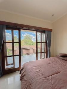 - une chambre avec un lit et une grande fenêtre dans l'établissement Ojek's Homestay, à Ubud