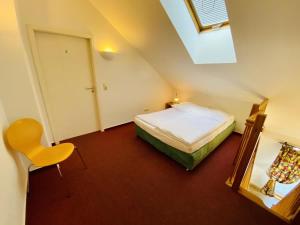 a small attic bedroom with a bed and a mirror at Landhaus Immenbarg, Alter Strom in Warnemünde