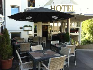 un restaurante con mesas, sillas y sombrilla en Hotel Abalone, en Remscheid