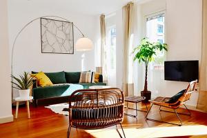 ein Wohnzimmer mit einem grünen Sofa und Stühlen in der Unterkunft Hola Valencia - Holiday Apartments in Valencia