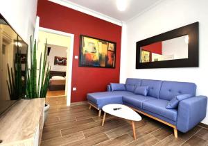 a living room with a blue couch and a red wall at Gazi Apartment with Breakfast in Athens