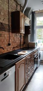 uma cozinha com armários de madeira e uma parede de tijolos em Mini dwupokojowy apartament vintage 23m2 em Poznań