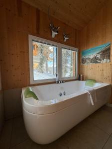 een groot wit bad in een badkamer met 2 ramen bij Chalet Bastion in Turracher Höhe