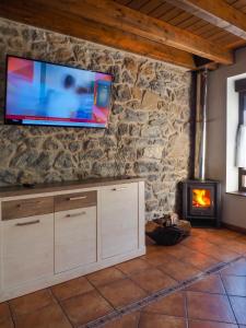 a television on a stone wall with a fireplace at Posada Real Pajares in Pajares