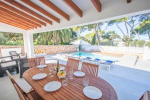 ein Esszimmer mit einem Tisch und einem Pool in der Unterkunft Villa Jomar by Sonne Villas in Cala Galdana